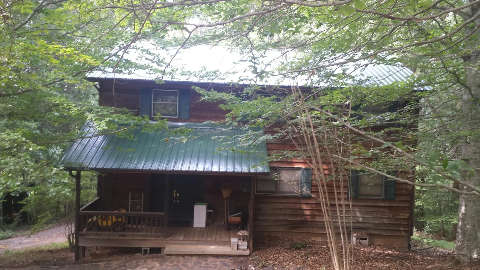 Green metal roof and covered porch on a log cabin in Celina