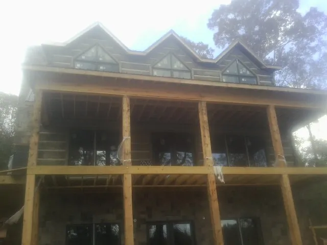 Dormers and porch framing on a large log home under construction — Roof Coating work by our crew in Celina
