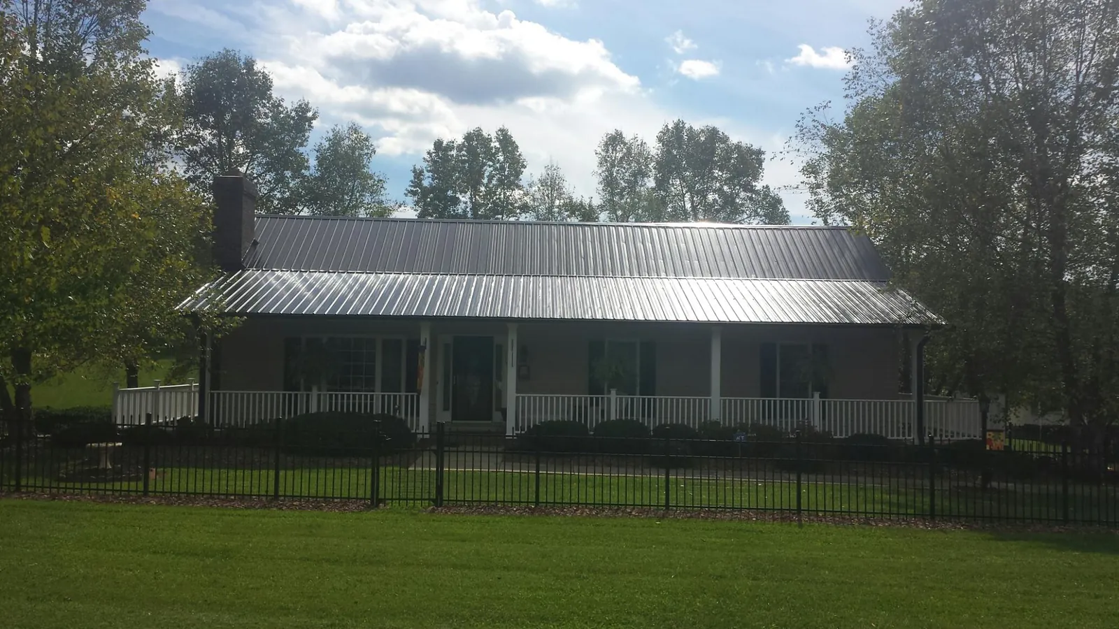 Gray metal roof on a brick ranch with a full width front porch — Gutter Guard Installation work by our crew in Celina